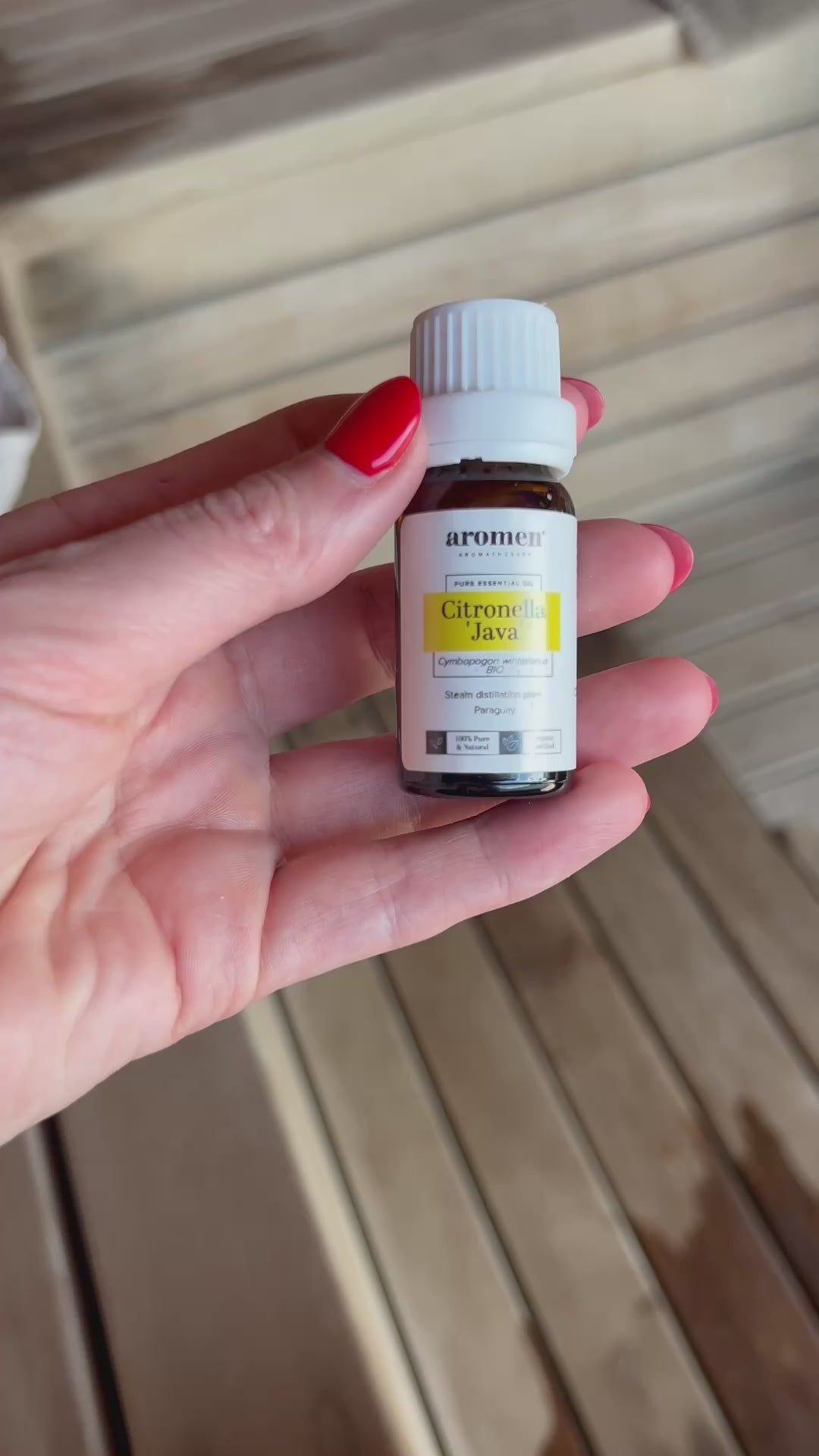 Citronella Java eterisk olje fra Aromen holdt i hånd i badstumiljø