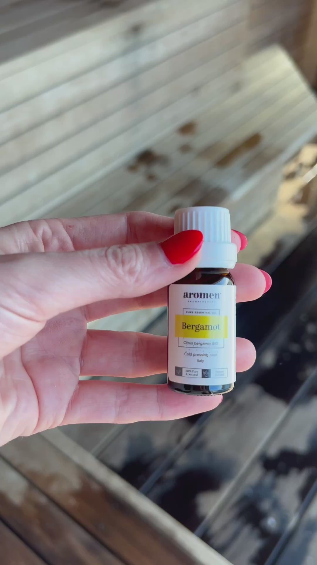 Bergamot eterisk olje fra Aromen holdt i hånd i badstumiljø